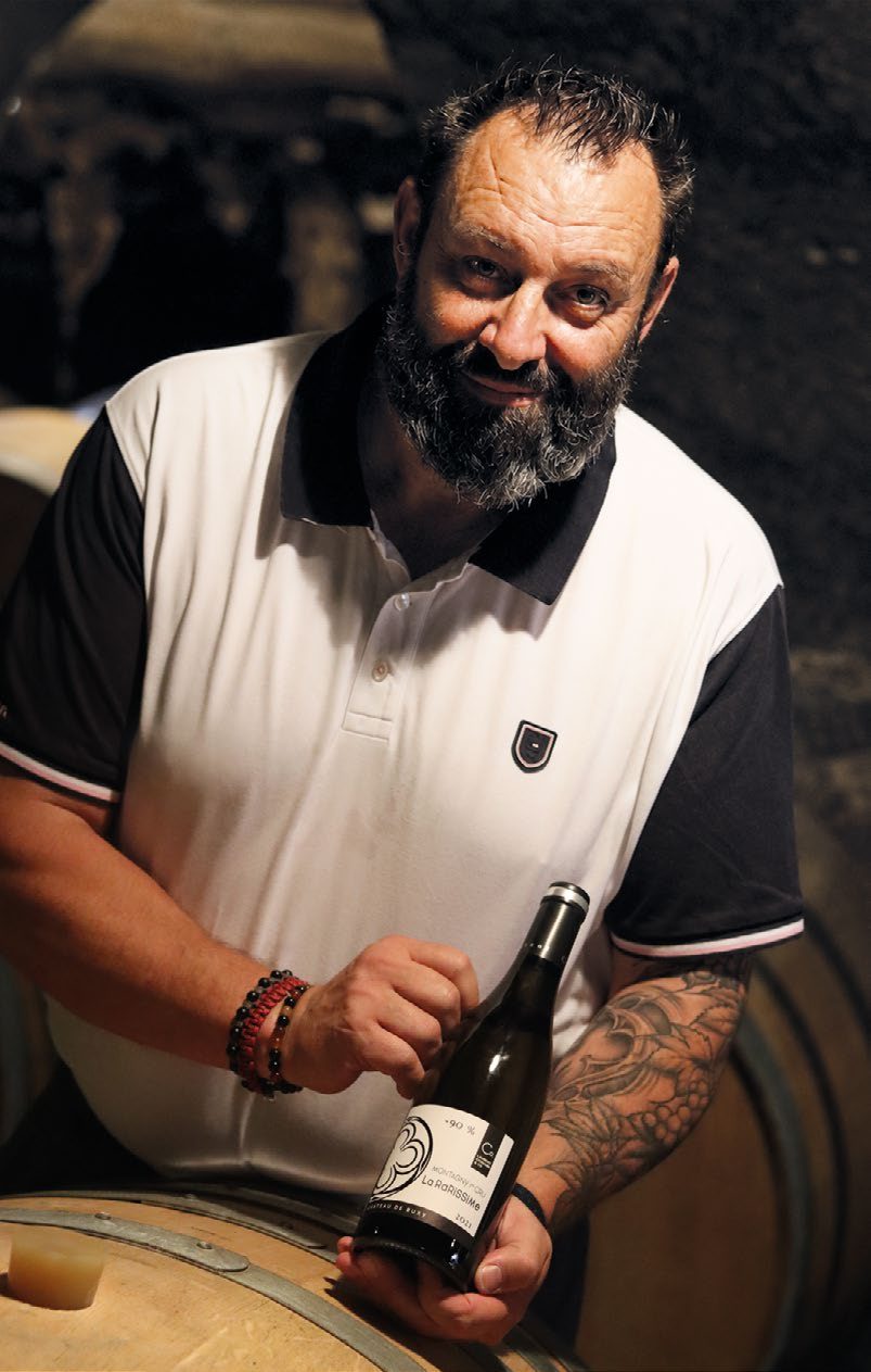 Laurent Cognard présente une bouteille dans la cave du Château de Buxy.