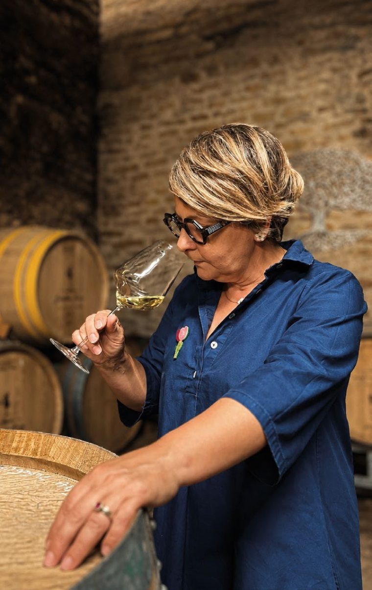 Géraldine Louise prélève un vin à la pipette dans sa cave, face aux fûts.