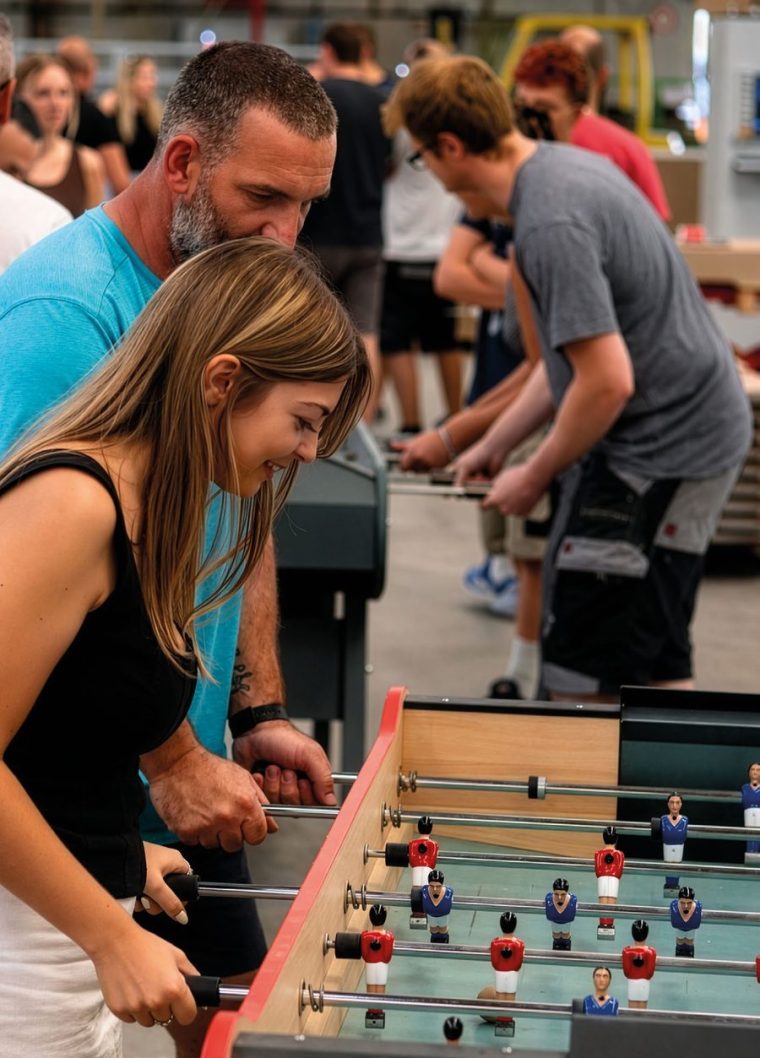 Partie de baby-foot René Pierre, joueurs de tous âges autour de la table.